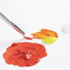 A paint brush with red and yellow paint on a white surface