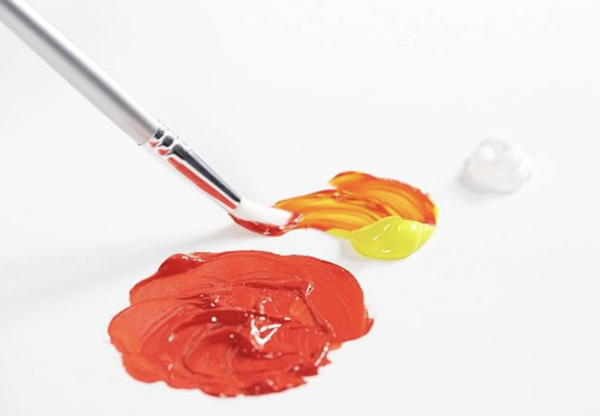 A paint brush with red and yellow paint on a white surface