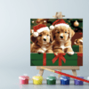 Paint by number Christmas puppies painting displayed on an easel, accompanied by paint pots and a brush, perfect for holiday crafting and creativity.