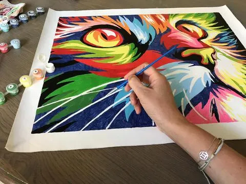 A picture of someone painting a colorful cat paint by number kit