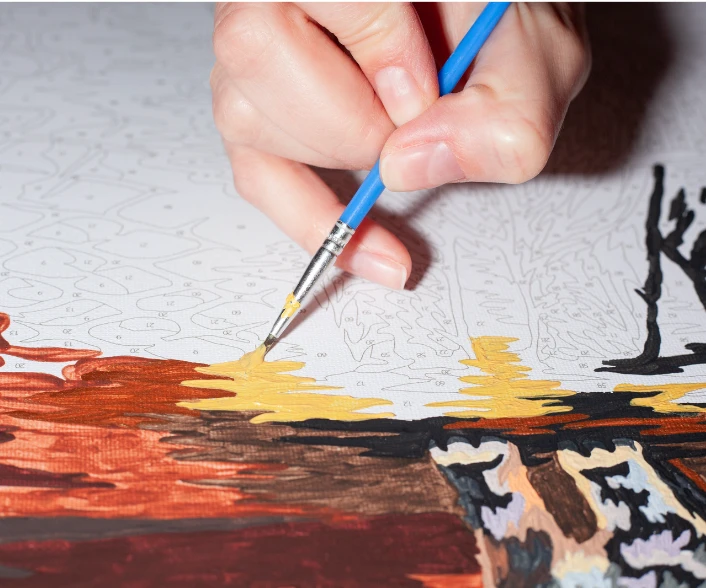 A person is painting a paint by numbers kit